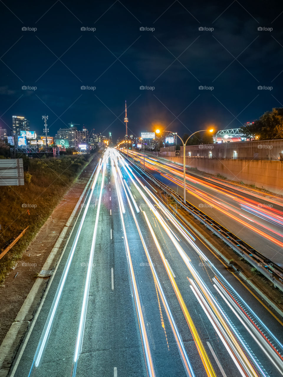 Car light trails down a highway leading towards Toronto’s skyline. iPhone long exposure photo.