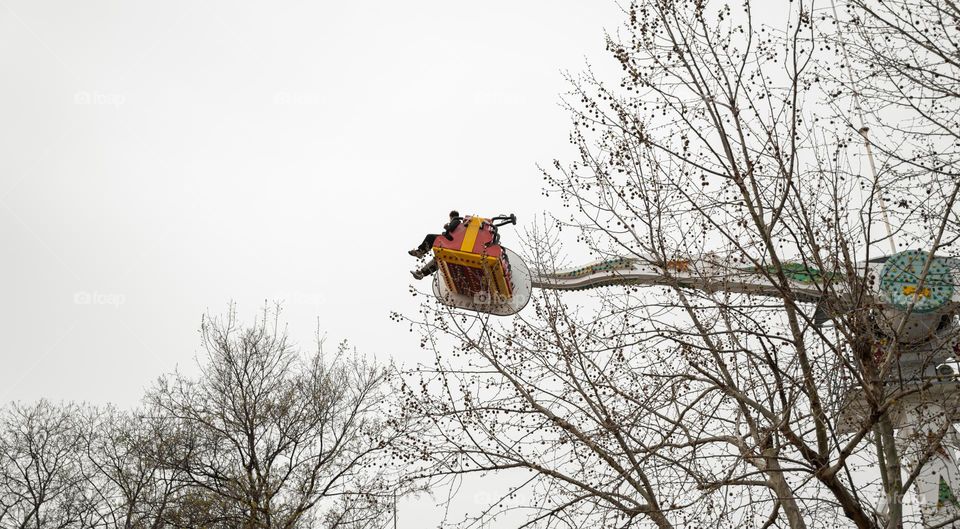 A couple is riding a roller coaster in amusement park.