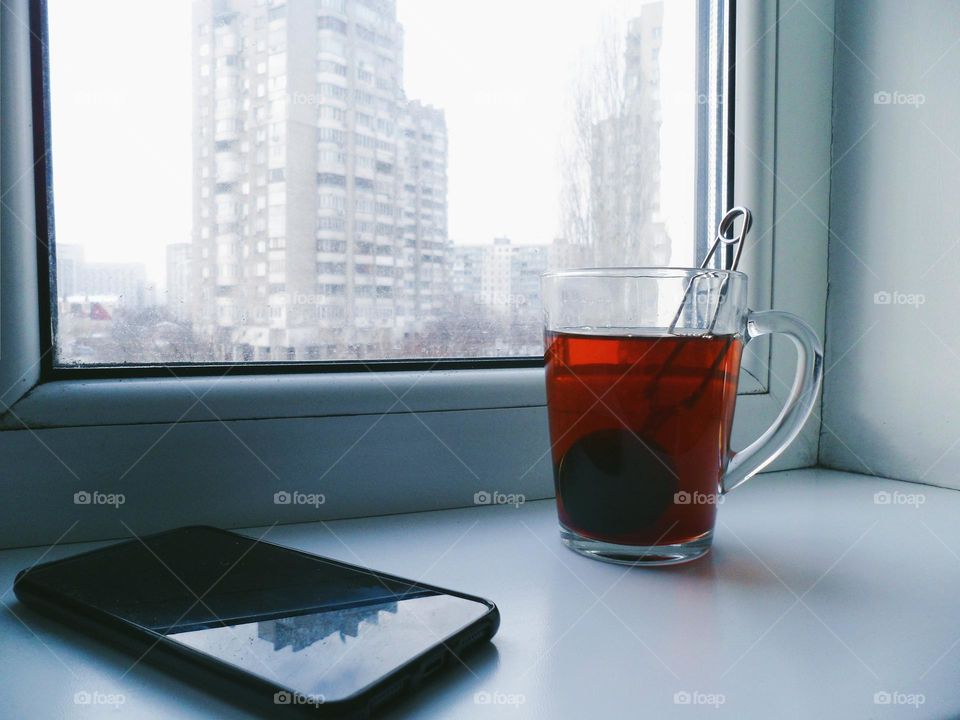 a cup of tea and a smartphone on the windowsill