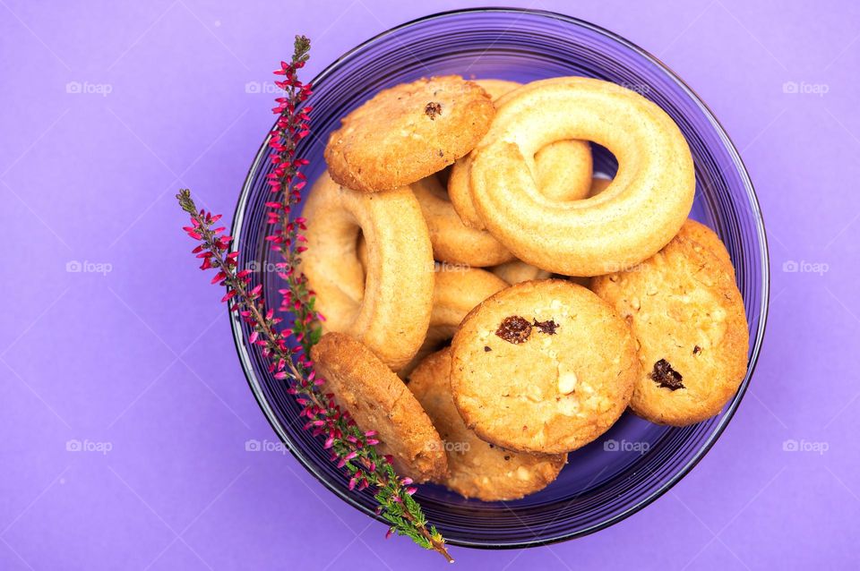 Round shaped butter cookies in glass dish on purple