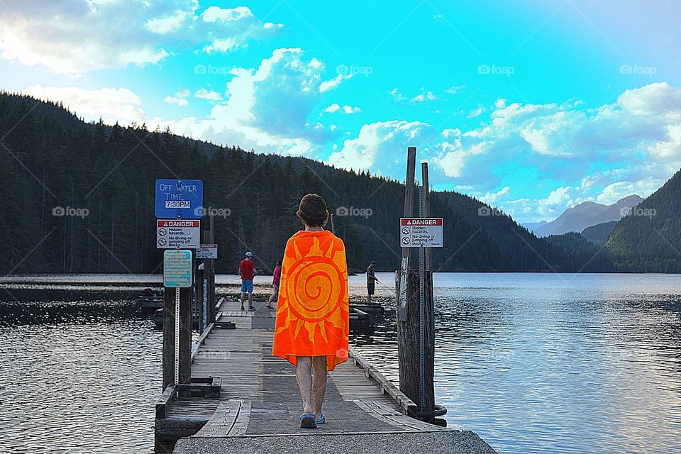 Boy in bright orange towel. Boy in bright orange towel walking dock at lake to swim