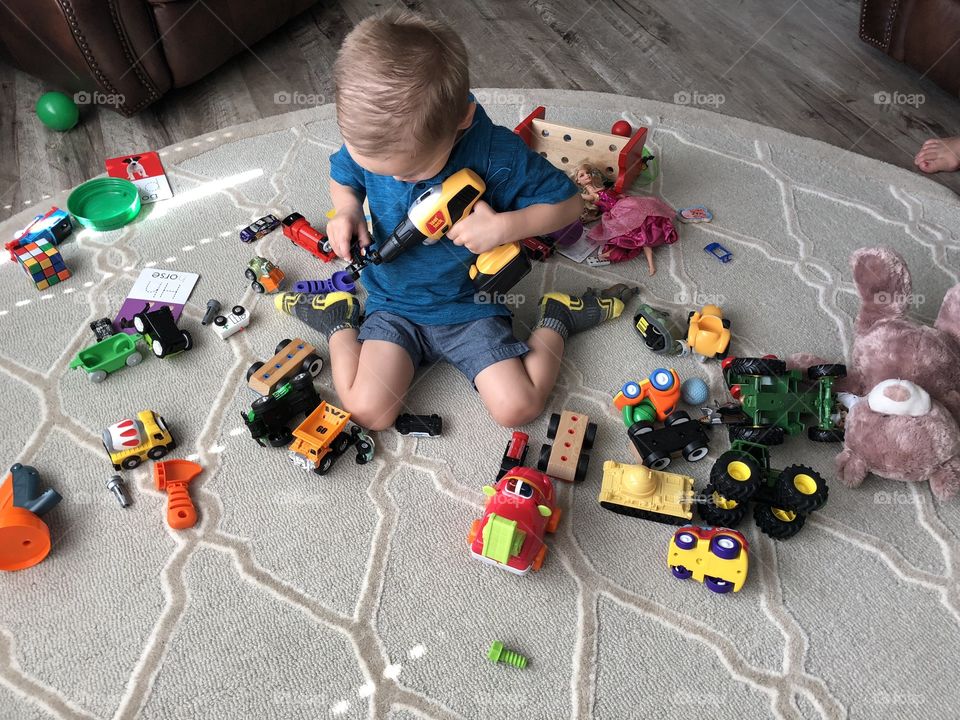 Cute boy with toys on rug inside the house 