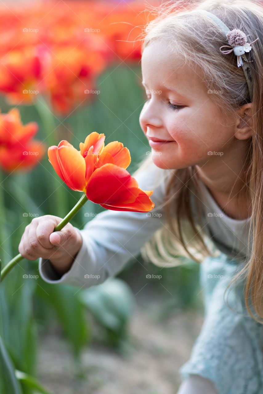 Girl sniffing tulip flower on field at spring