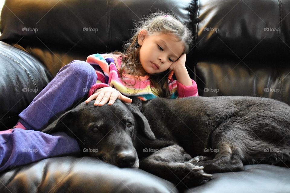 Close-up of a girl with her dog lying on sofa