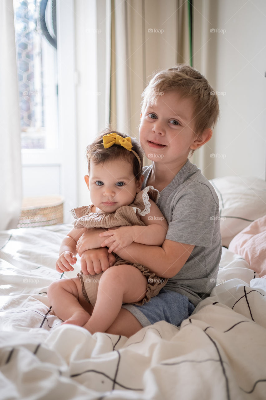 Infant baby girl in hug with her toddler brother