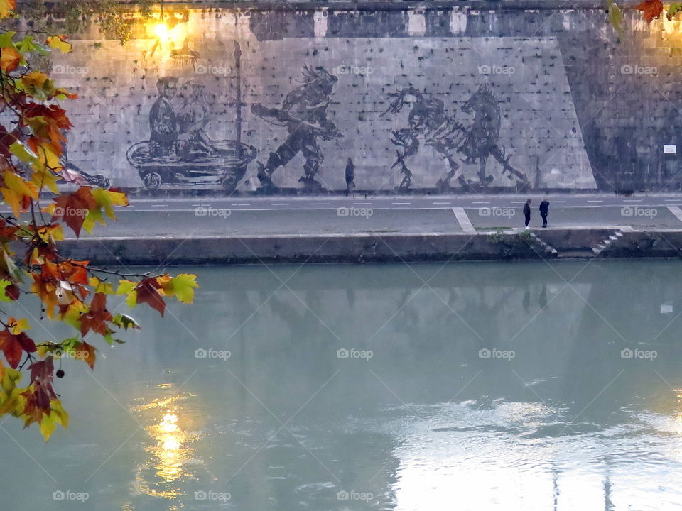 walking in the evening on the riverside in front of the street art mural