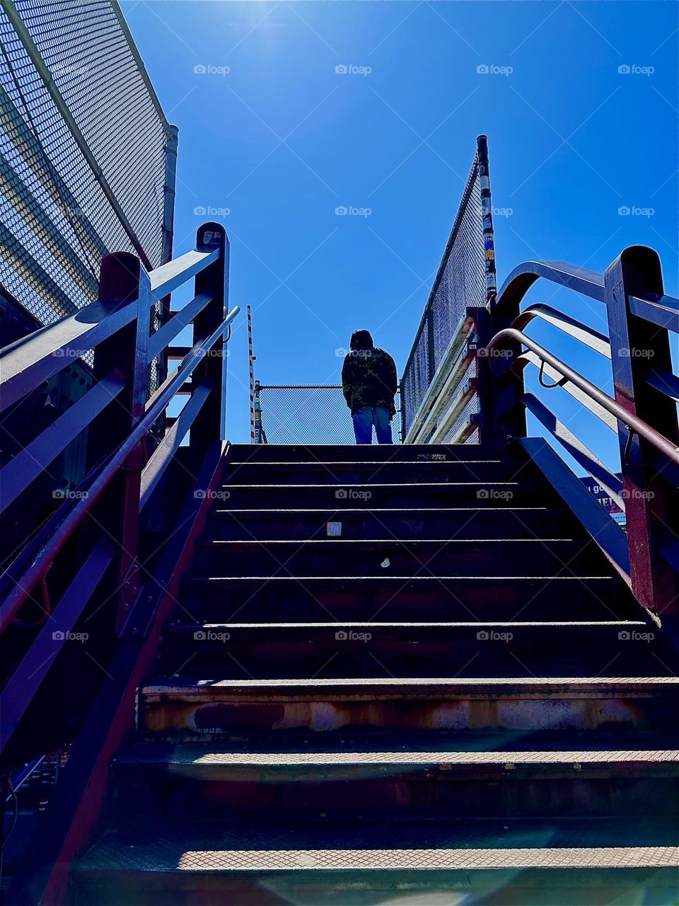 This is the last stretch of climbing the red metal staircase of the “Pulaski Bridge” at “Newtown Creek” in LIC, Queens. At the top of the stairs the pedestrian lane awaits. Hypnotic Productions