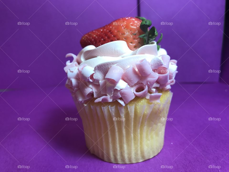 Cupcake pink icing purple background strawberry yellow cake