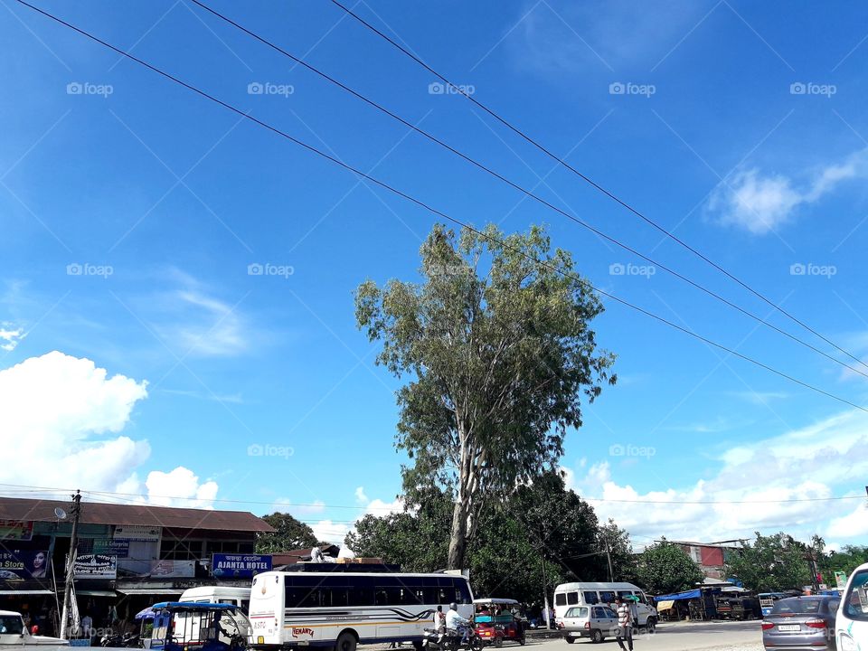 Blue sky, white cloud under peopls busy a small city with bus, car etc.