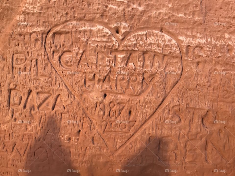 Multiple carvings on a red granite cliff top.