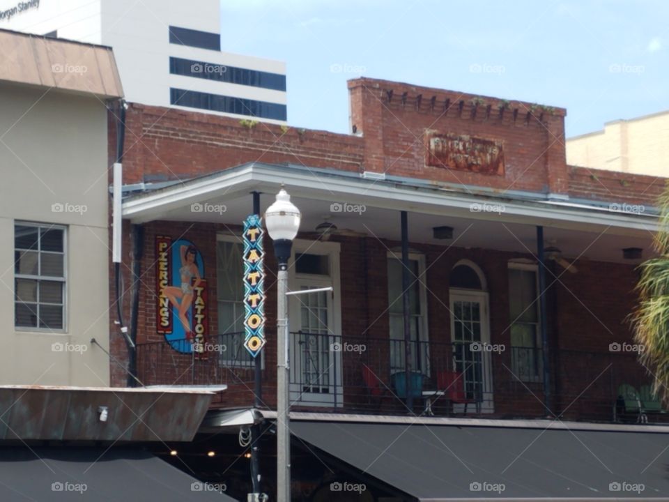 Tattoo parlor on second story of a brick building with a balcony in a city in Florida