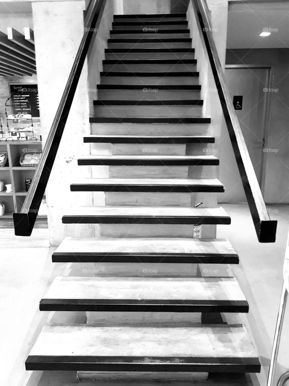 A black and white photo of modern, glass-styled stairway with handrails.