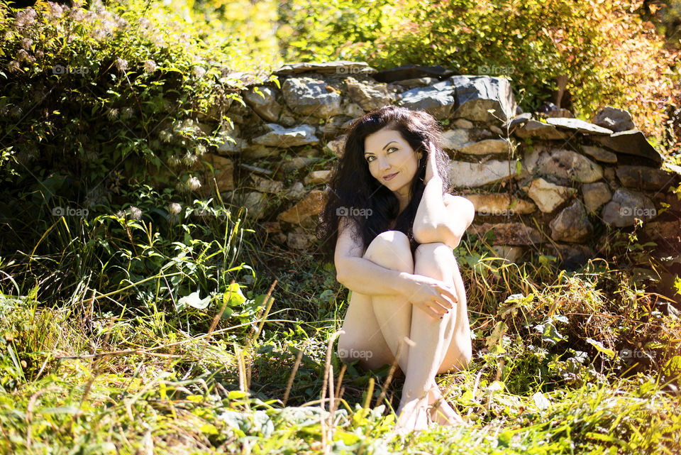 Mid adult woman sitting in front of stone wall