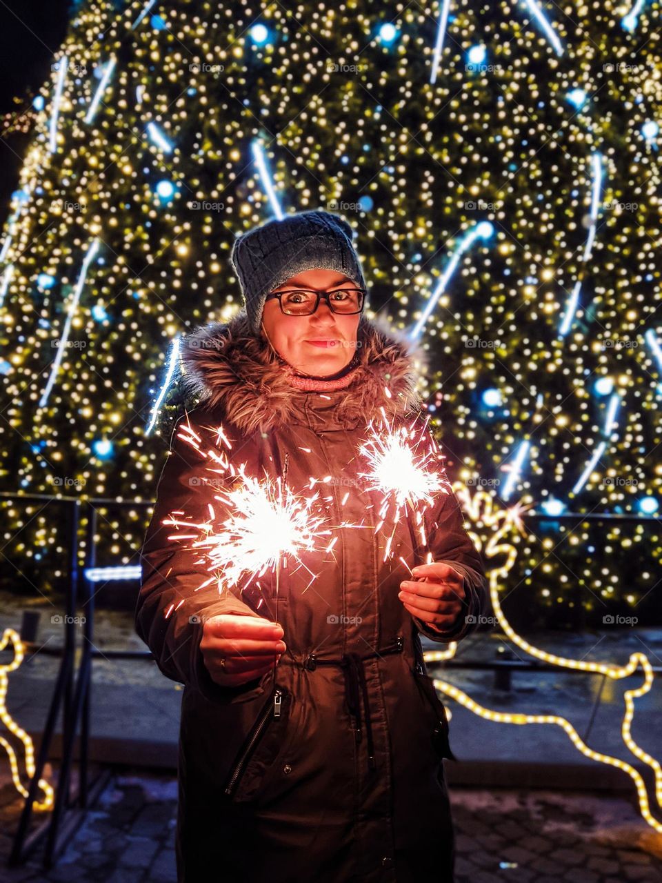 Portrait of young happy, beautiful woman in eye glasses in Christmas,  New Year city with illumination and garlands