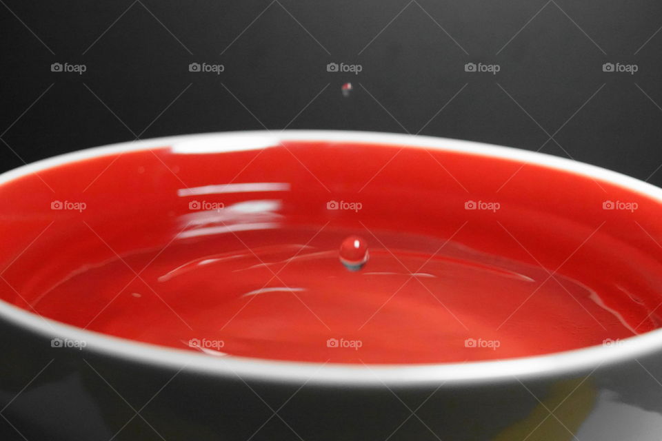 Water drops and red bowl black background caught in mid air.