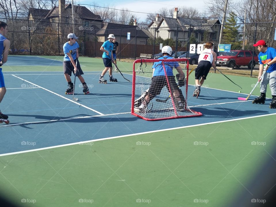 boys playing hockey on tennis court