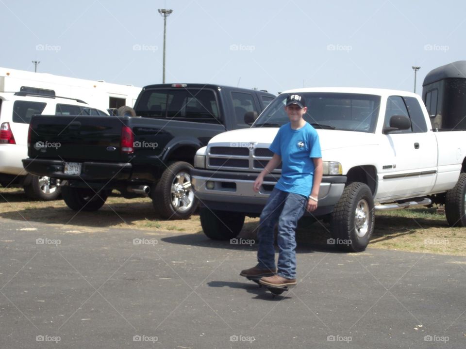 Boy and his skateboard at a horseshow in between rides