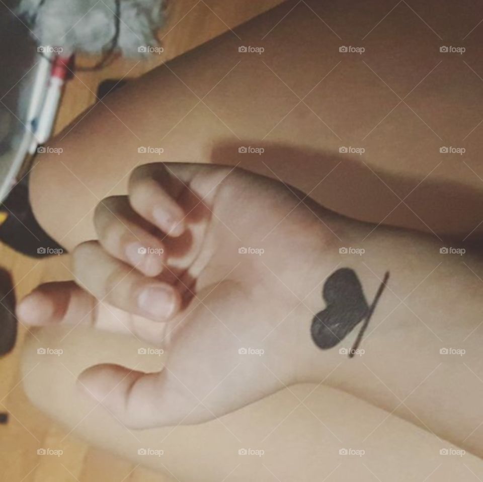 underlined filled in black ink heart. underlined heart project. marker? tattoo? filter? hand spread over legs, two fingers extended slightyly