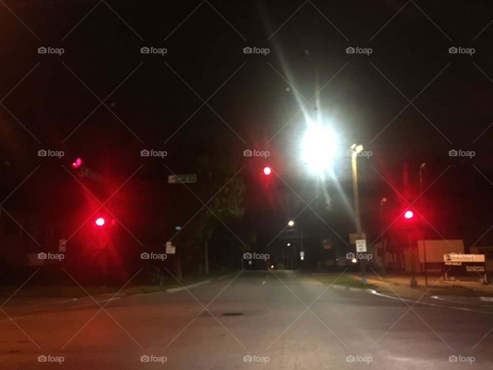Red traffic light on empty road at night