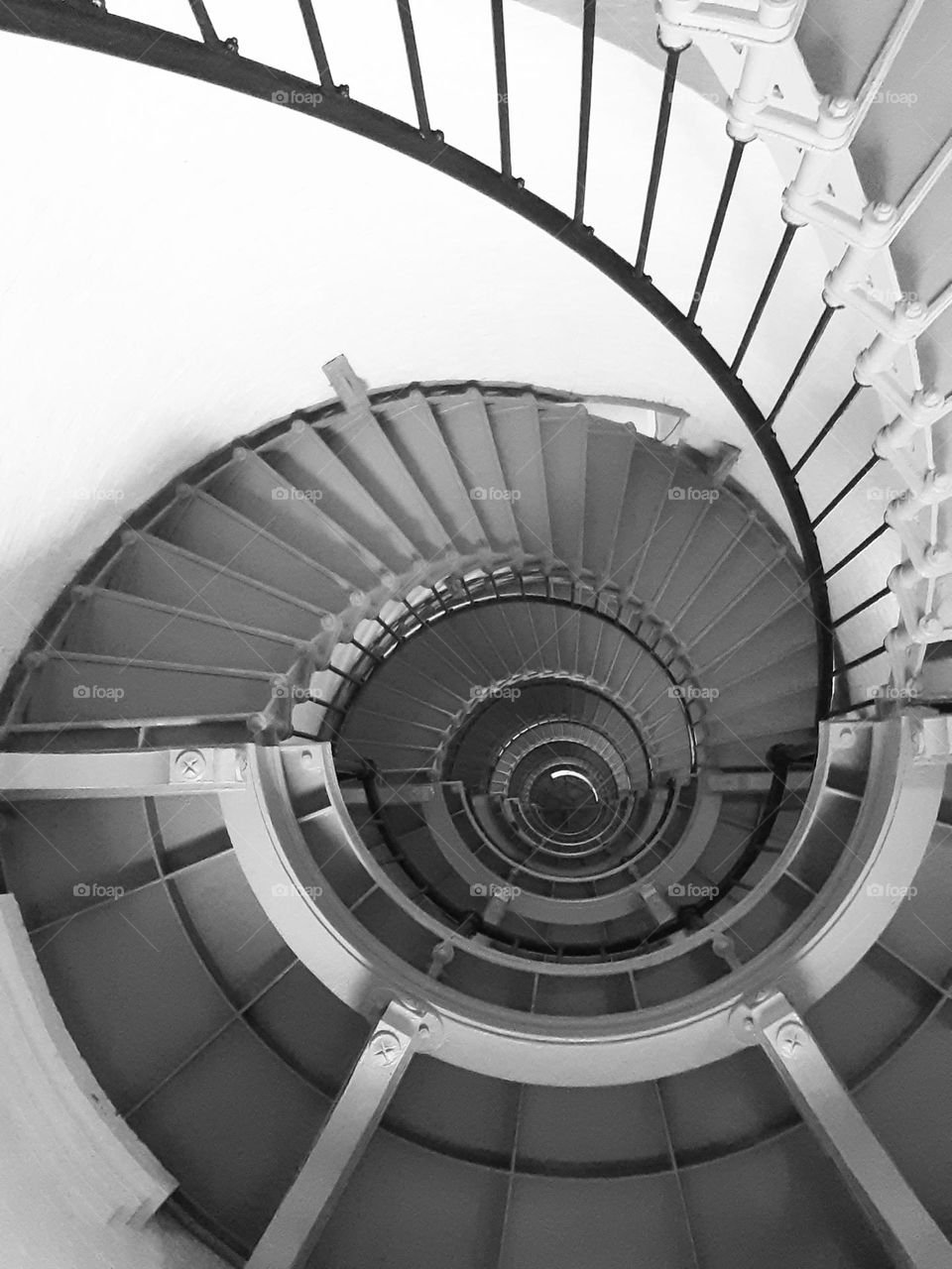 A black and white photo of the steep spiral staircase of the Ponce Inlet Lighthouse.