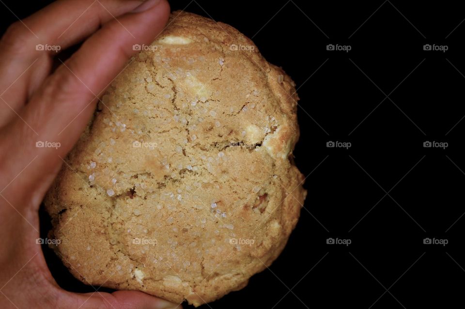 Creamy sweet macadamias cookie on hand with black background with white sparkling sugar on top 🤤