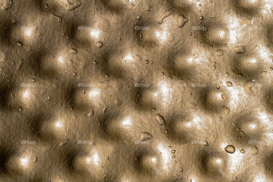Close-up of metallic bumpy texture with water droplets