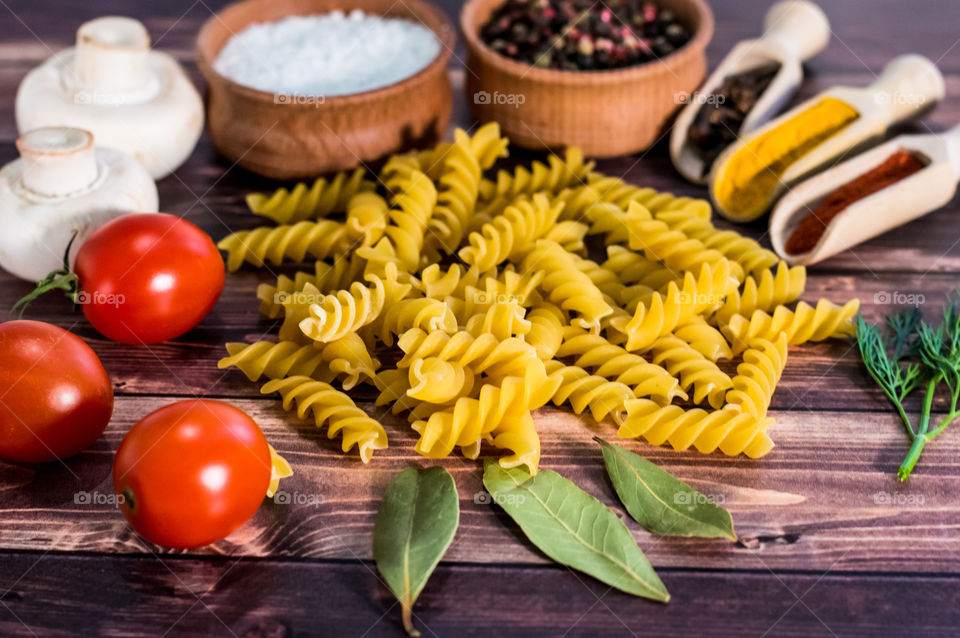 Raw pasta with ingredients and wooden accessories