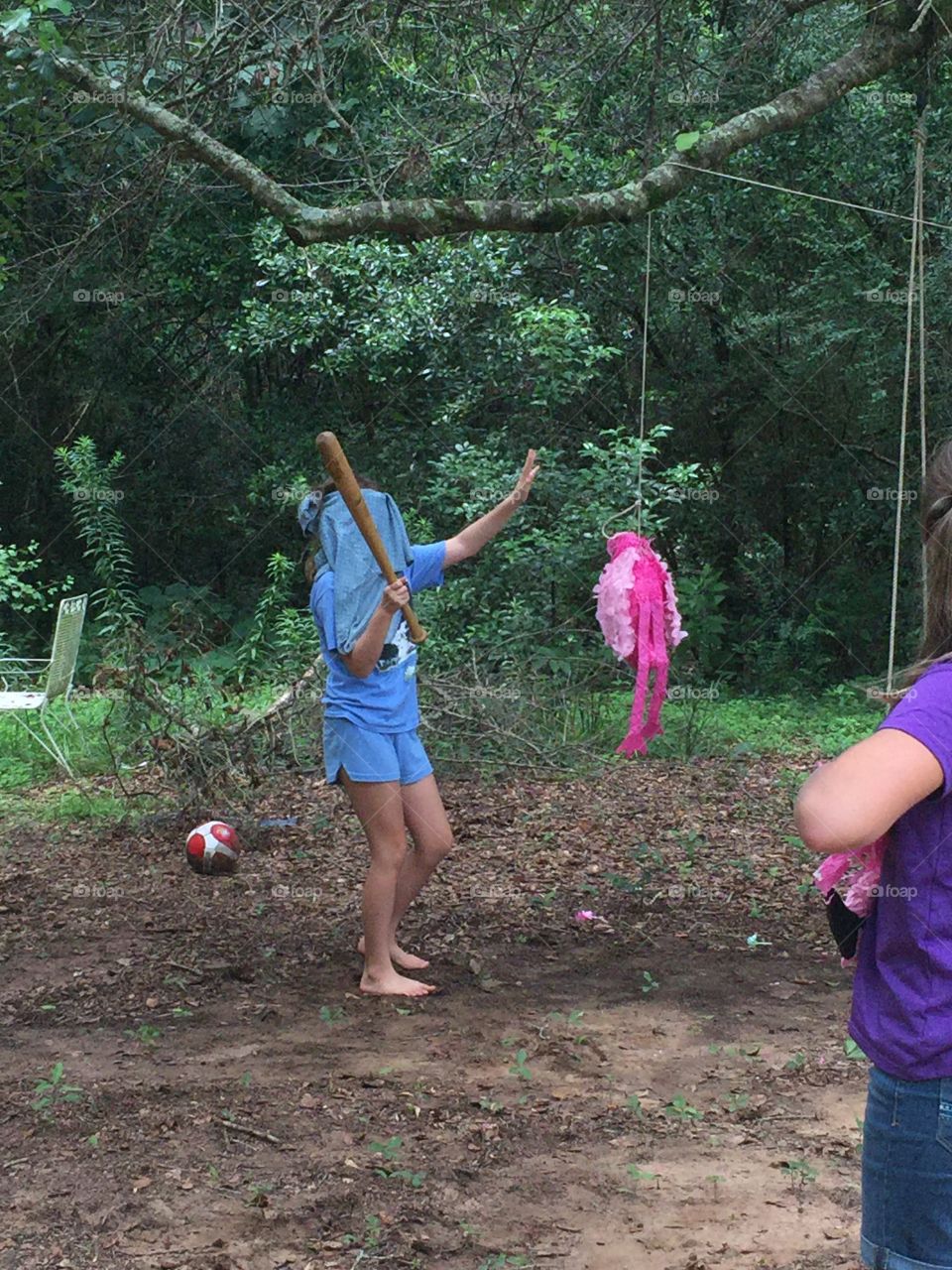 Little girl swinging a piñata at a birthday party