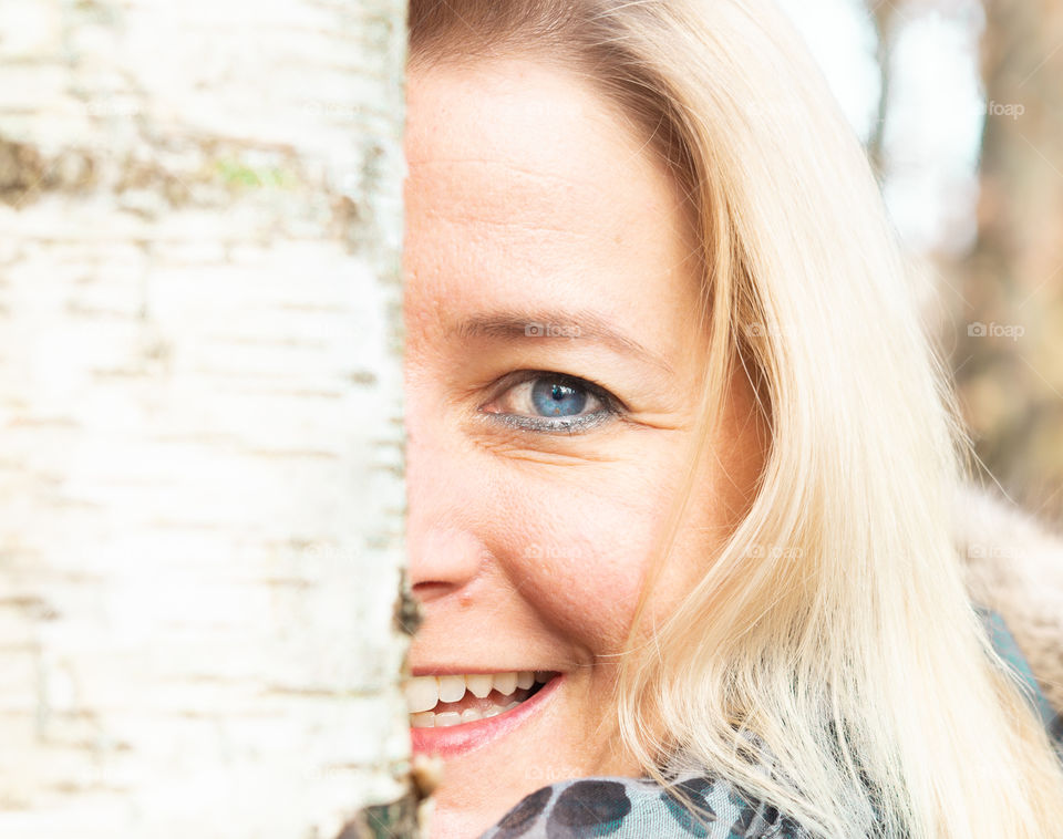 half face of a woman with blond hair and a white birch