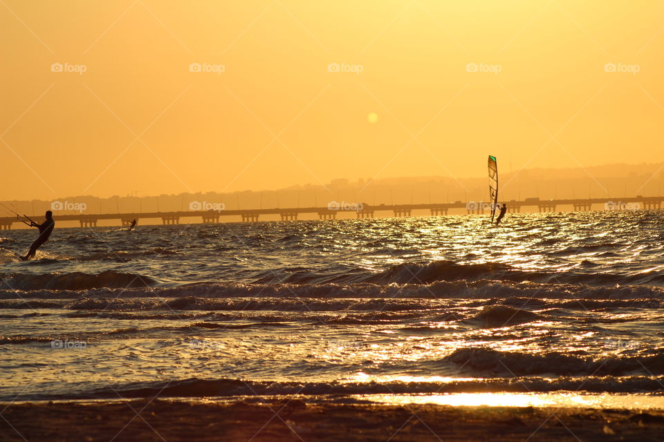 Water sports windsurf and kitesurf in a beautiful beach sunset 