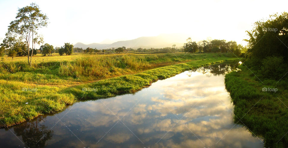 Cloudy Sky Reflecting On The River Surface.