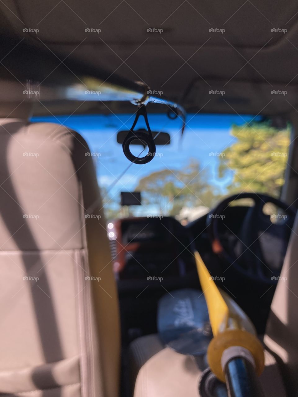 On the road: backseat perspective through a fishing rod of a car filled with kayaking gear.