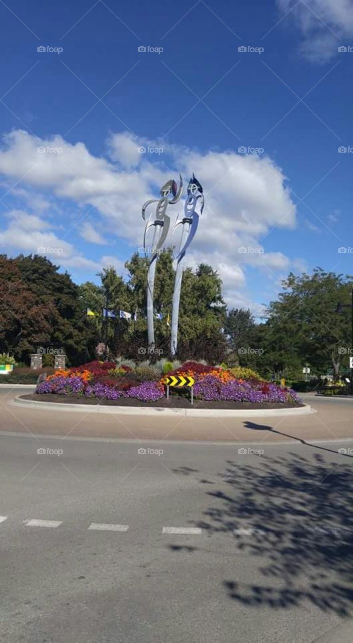 The colourful roadway roundabout with flower gardens and metal sculptures.
