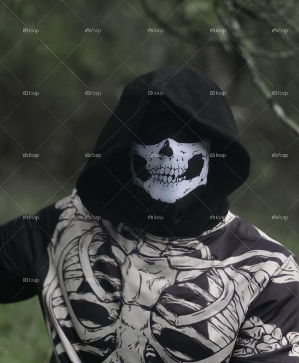 A person dressed as a skeleton with a dark hood covering their eyes