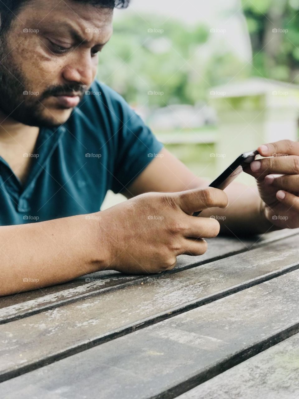 Person looking at phone at outdoor table 