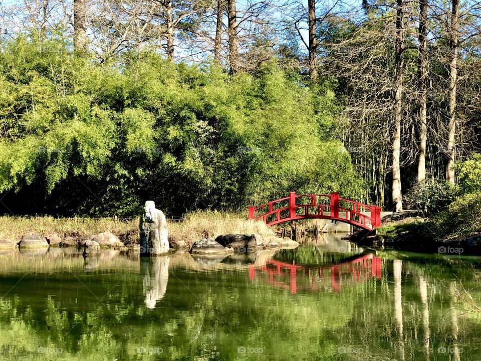 Red footbridge reflecting in water garden 