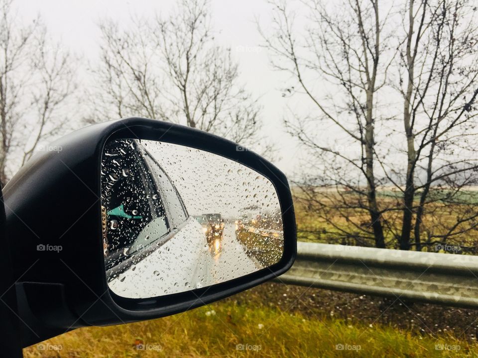 Car mirror covered in raindrops 