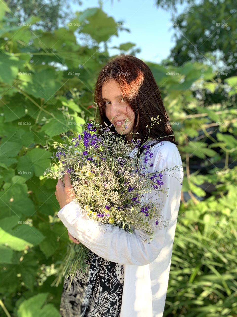 iPhone portrait of pretty girl with bouquet of wild flowers 