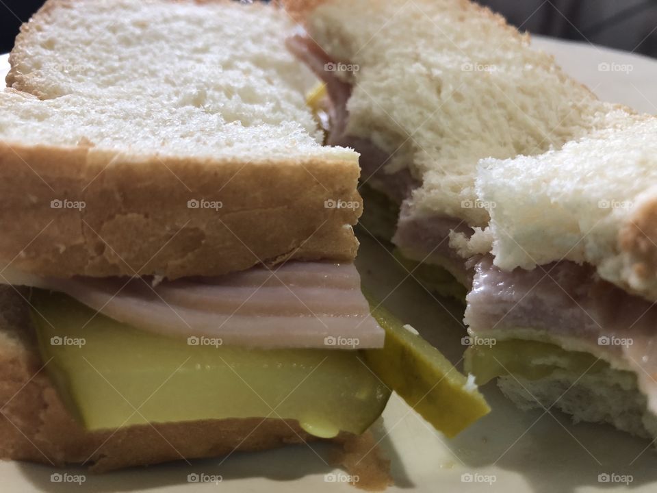 Sliced turkey and cheese sandwich with mayo and pickle