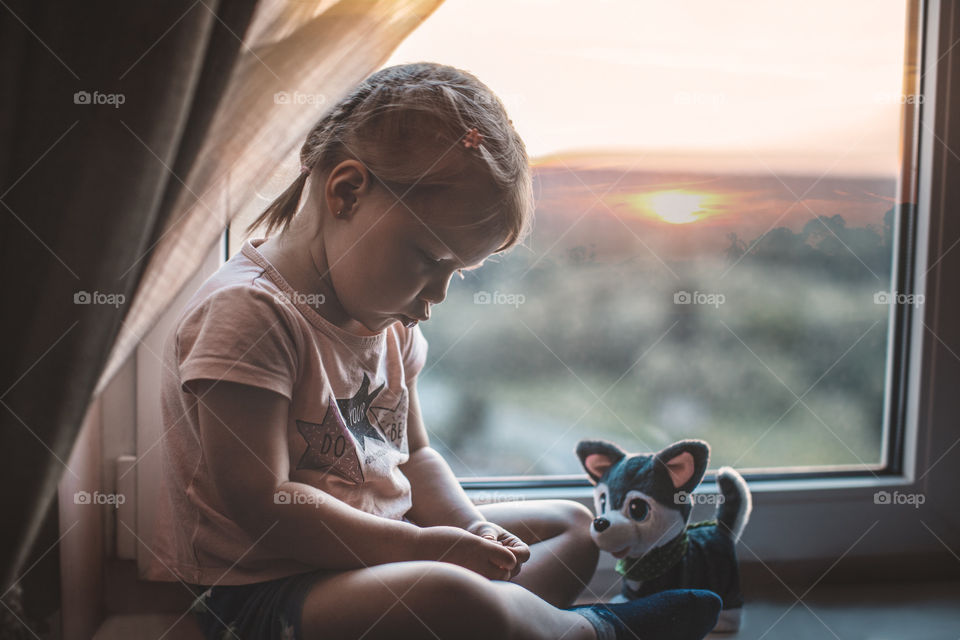 girl sitting by the window with her favorite toy