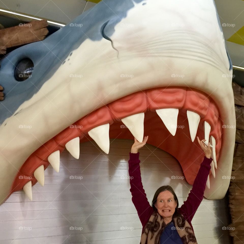 Woman standing under fake fish