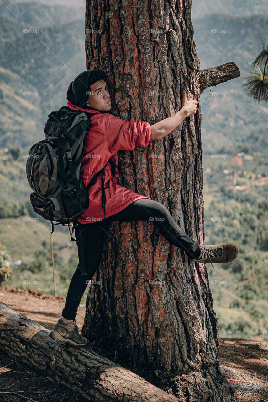 Boy clinging to a tree in the middle of the mountain