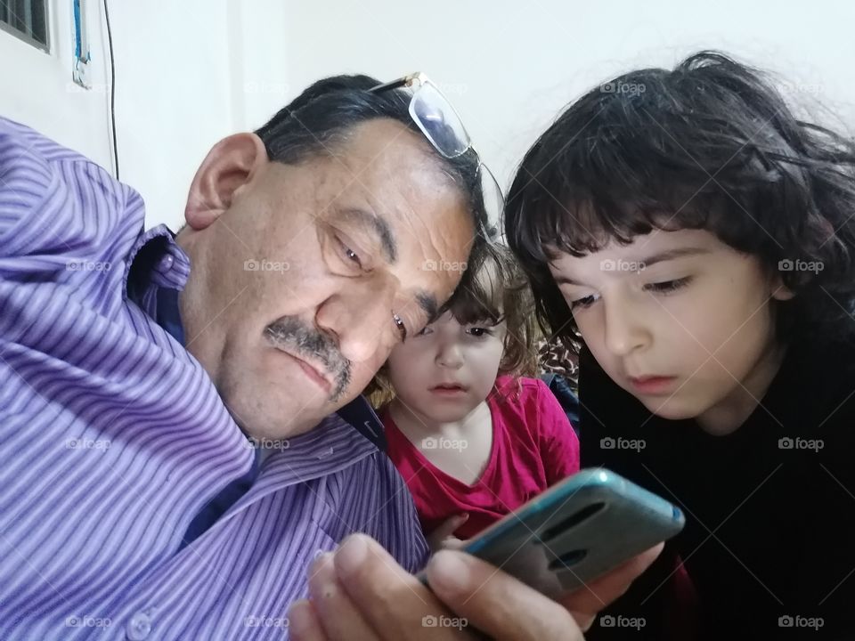 جد واحفاده يشاهدون الجوال  Grandfather and his grandchildren watching the mobile