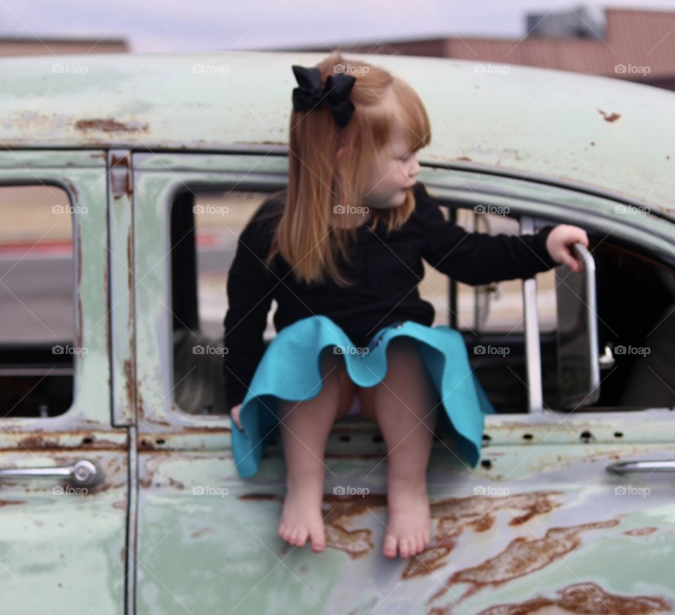 Young female redhead sitting in car window 