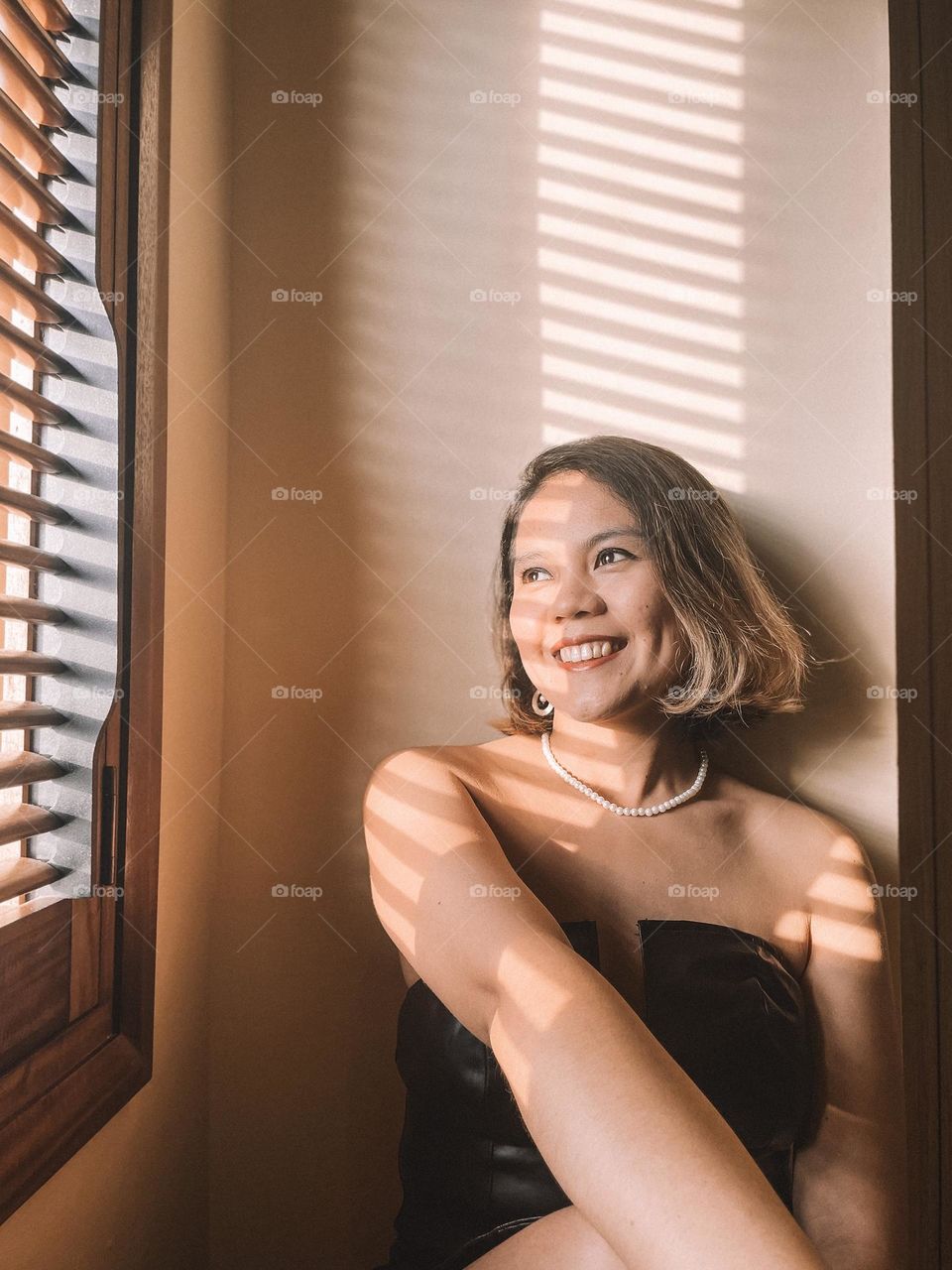 A candid portrait of a girl beside a window with sun streaks