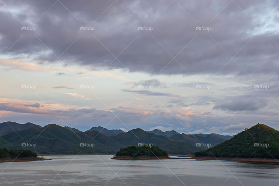 The reflection of the Sun and the clouds on the sky Background mountain and water at Kaeng Krachan dam in phetchaburi , Thailand.