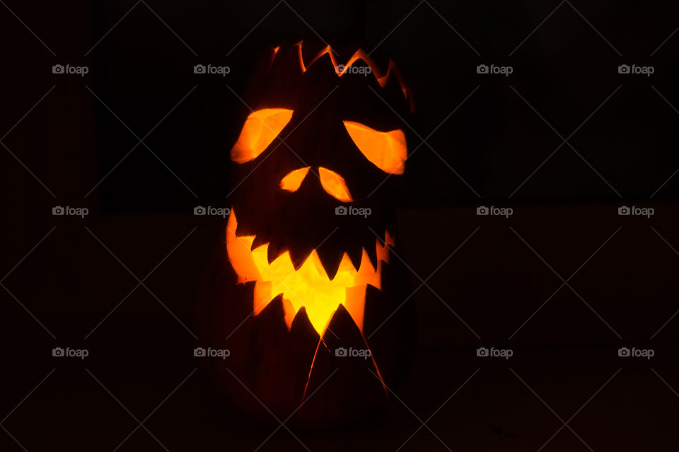 Evil pumpkin face for Halloween in a dark room at night close-up.