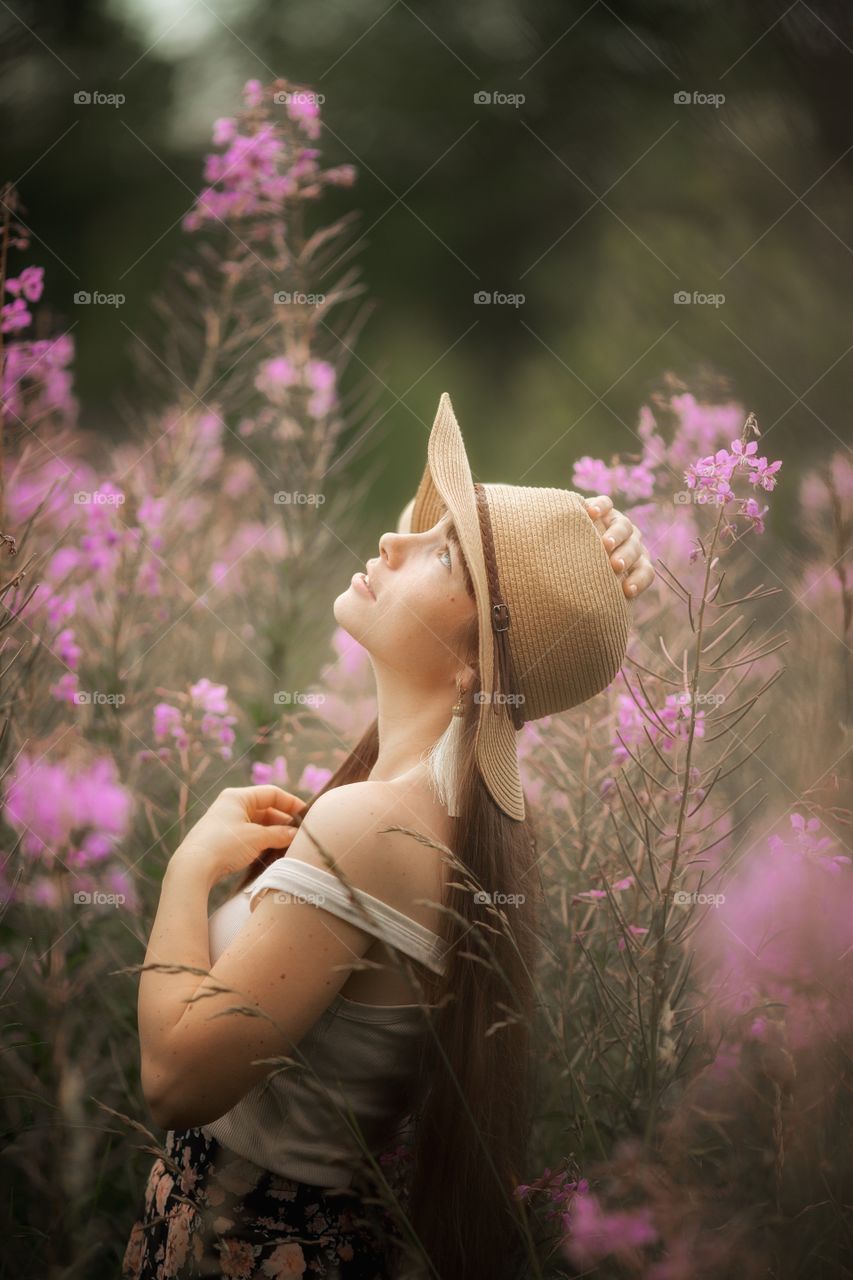 Beautiful young woman in a field of blossom flowers in boho style