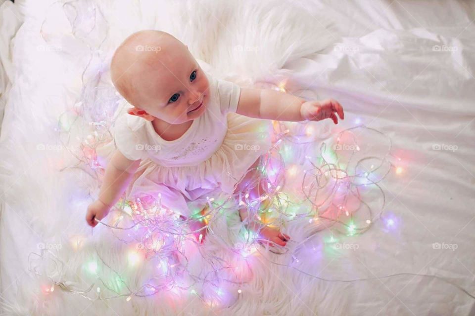Toddler playing with colourful Christmas lights