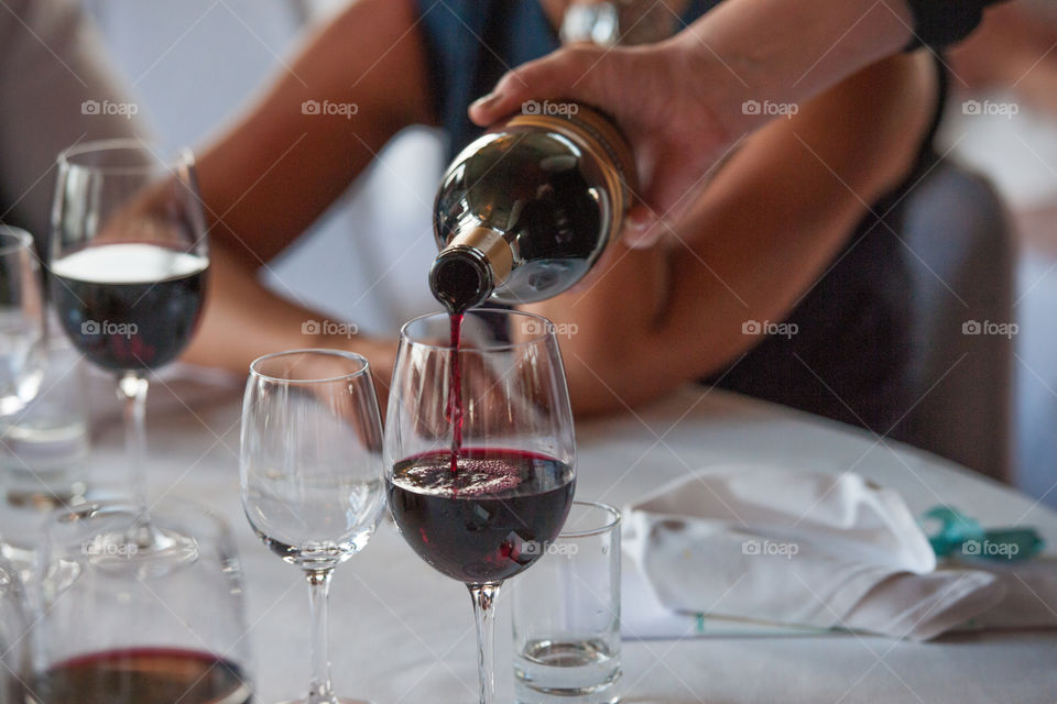 Someone pours a glass of red wine at dinner.